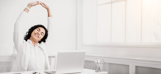 Relaxation At Work. Calm latin businesswoman stretching on chair at office during break, hands up....