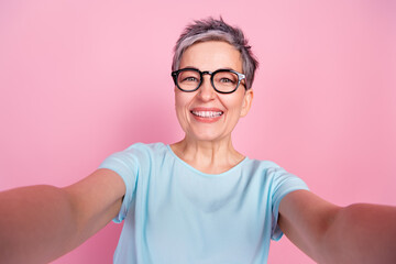 Photo of pretty aged woman make selfie toothy smile blue t-shirt isolated on pink color background