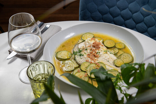 Amberjack fillet dish with courgettes served on an elegant white plate.
