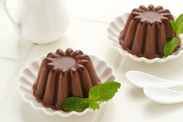 Chocolate pudding with mint leaf, served on a small white plate
