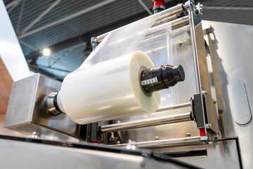 Plastic film, packaging industrial machine in factory. Roll of polyethylene film.