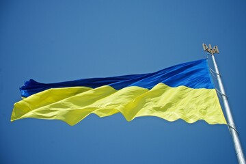 a large Ukrainian flag against the background of the blue sky