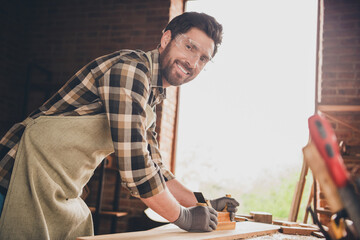 Photo of workman wood worker guy using tool for working with plank in garage indoors