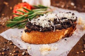 Delicious bruschetta with black truffle cream and parmesan cheese on wooden table