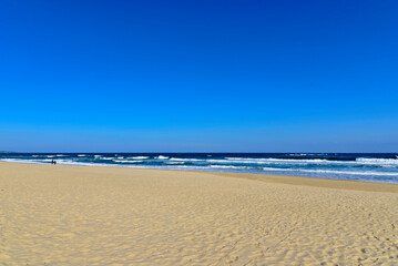 Winter view of a couple and sea waves at Hyangho Beach of Jumunjin near Gangneung-si, South Korea
