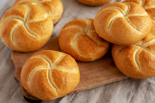 Homemade Kaiser Rolls on a wooden board, side view.