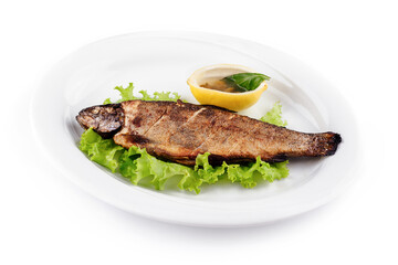 Grilled trout served on bed of lettuce with lemon and condiment
