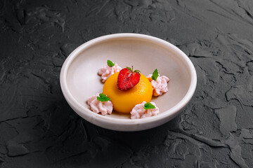 Delicious mango panna cotta dessert with strawberry and mint on black background