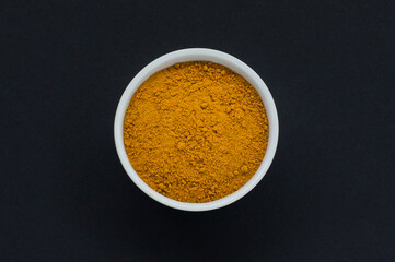 Close up of curry powder in a white bowl on a black background
