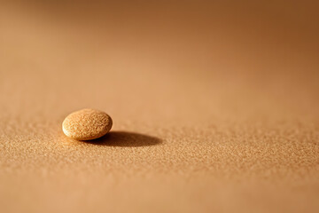 A peaceful beach scene with a close-up of a seashell and a ball resting on the sand, surrounded by smooth pebbles and stones, representing balance and harmony in nature