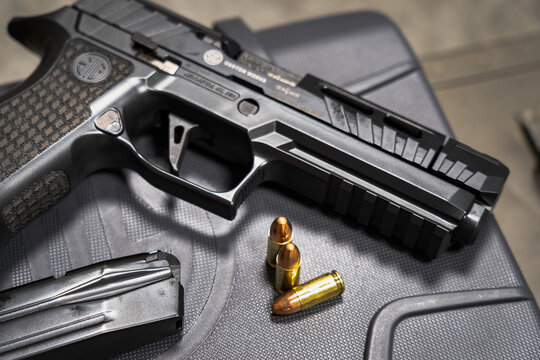 Baltics August 23, 2024. Modern tactical sport pistol Sig sauer and 9mm cartridges. Close-up photo.