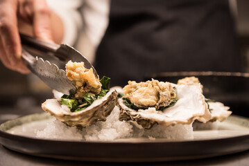 Fried Oysters being prepared on plate in restaurant kitchen