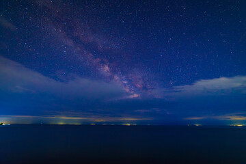 Fototapeta premium starry night sky with few clouds over large mountain lake at night