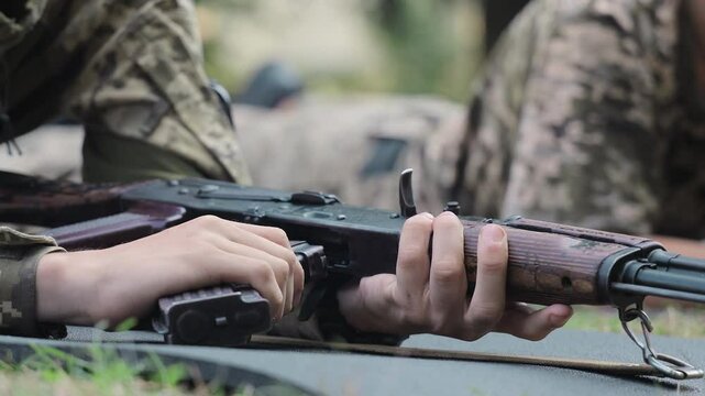 Soldier preparing rifle during training in prone position. A close-up of a soldier preparing an assault rifle while lying prone during a training exercise.