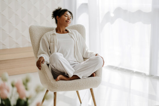 Fototapeta Young woman relaxing in armchair at home