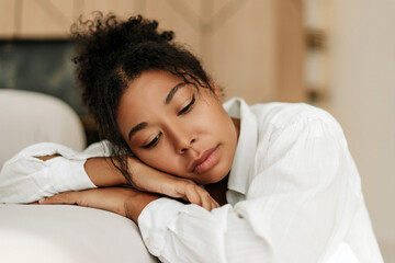 Young black woman feeling sad and resting head on hands