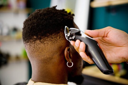 Professional barber styling black man's hair at coastal shop