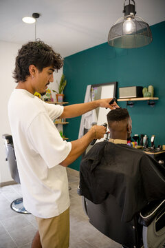 Barber gives a haircut to a black man in a modern shop