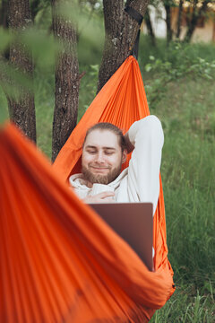 Young man relaxing in a hammock with a laptop