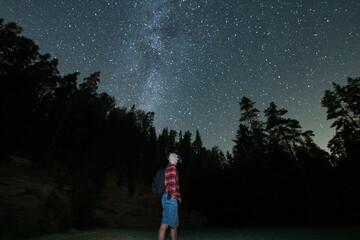 Obraz premium Night scene, civilian man with night vision goggles on his head in night forest with starry sky.
