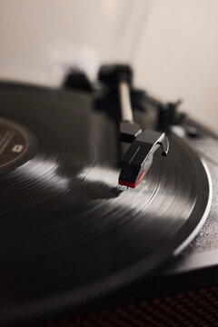 Turntable headshell and tonearm playing music from a vinyl record with its typical vintage sound