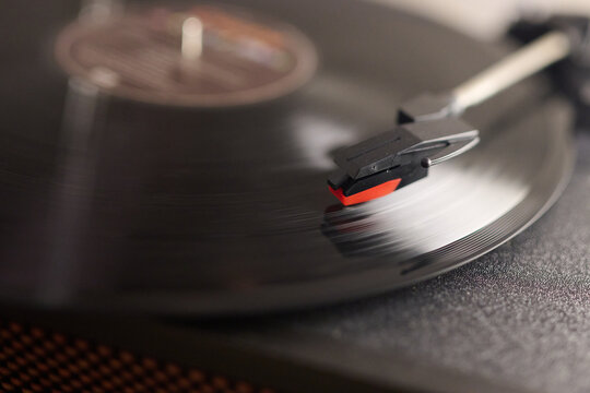 Close up view of a turntable headshell playing music from a vinyl record with its typical vintage sound