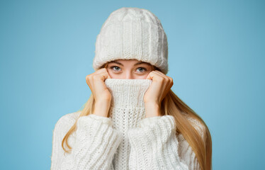 Blonde girl in winter clothes covering her face with sweater, warming up during cold season, yellow...