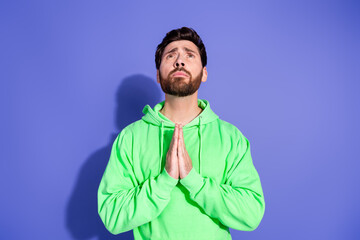 Photo portrait of handsome mature age god prayer man wearing green hoodie palms together pleading isolated on violet color background
