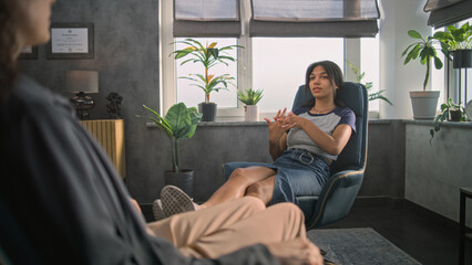 Relaxed African American teen girl sits in chair, shares positive emotions with psychotherapist, finds solution during counseling therapy session. Psychotherapy and psychological help. Mental health.