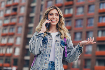 Portrait of pretty young girl chatting phone backpack wear denim jacket walk street outdoors