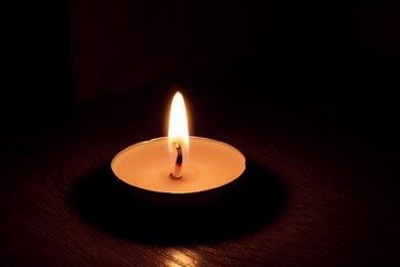a small candle burns on a dark background
