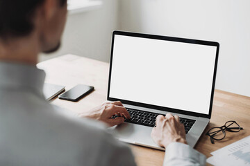 Young man using laptop computer with blank empty mockup screen. Business man working at home....
