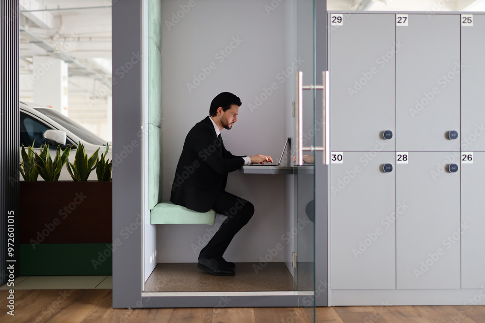 Aufkleber a man in a suit is sitting at a desk in a cubicle. he is using a laptop computer