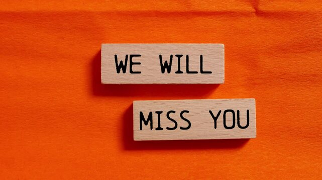 We will miss you message writing on wooden blocks on orange background. Conceptual we will miss you symbol. - Powered by Adobe