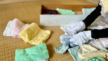 たくさんのタオルなどを片づける軍手をした手元