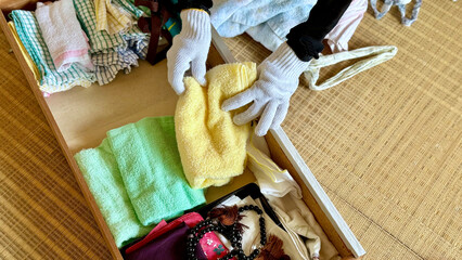 たくさんのタオルなど引出しにしまう軍手をした手元