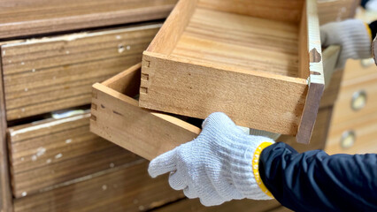 古い小さな引出しを重ねて持つ軍手をした手