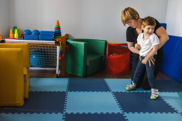 Smiling child with cerebral palsy engages in physical rehabilitation activities with physical...
