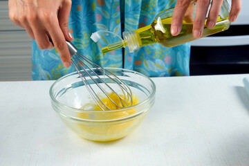 Woman cooking homemade mayonnaise adding olive oil into bowl to mixed mass, hands close-up. Preparing sauce for salad, meat dishes. Dressing for different dishes. Culinary, cuisine concept.