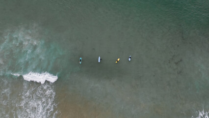    Surfers catching waves, waiting for a wave to come in the middle of the ocean near the beach during a beautiful day