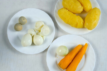 Ingredients for salad, dish, cooking food eggs, vegetables on plates on kitchen. Boiled potatoes, carrots, fresh pilled onion, eco healthy products for recipe. Cuisine, culinary concept.