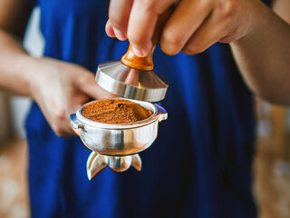 Close-up of hand Barista cafe making coffee with manual presses ground coffee using tamper at the coffee shop