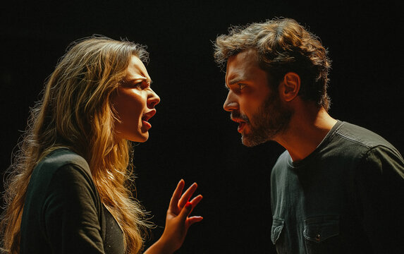 A man, yelling with his mouth open, argues with a woman with long, wavy hair, both looking angry and wearing dark clothes against a black background.