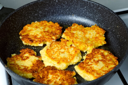 Potatoes pancakes, draniki cooking in frying pan on gas oven on kitchen at home. Preparing fresh dish. Cuisine, culinary, recipe. Traditional Russian food on lunch dinner fry on vegetable oil.