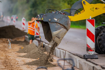 Construction equipment front loader excavation bucket draping cement for road works on industrial...