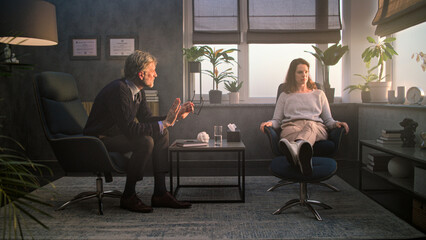 Fototapeta premium Upset and stressed woman discusses psychological trauma with therapist during counseling session. Mature psychologist talks to female patient, asks questions, provides psychotherapy. Mental health.