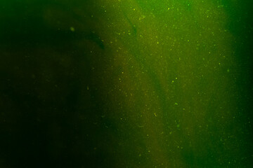 Abstract water background with green glow Chaotically moving glowing dust particles in water....