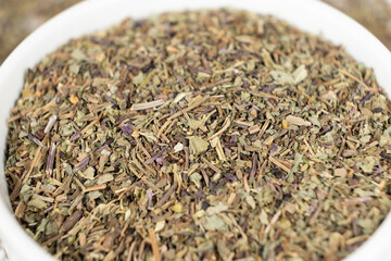Seasoning dried basil in a plate, macro chopped basil