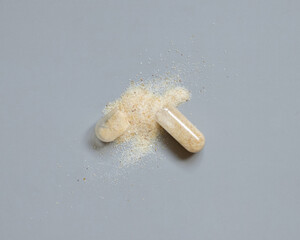 Opened Medical capsule to show beige powder on grey top view. Dietary supplements