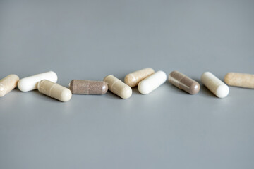 Mix of beige and brown medical capsules in a line on grey closeup. Dietary supplements and vitamins
